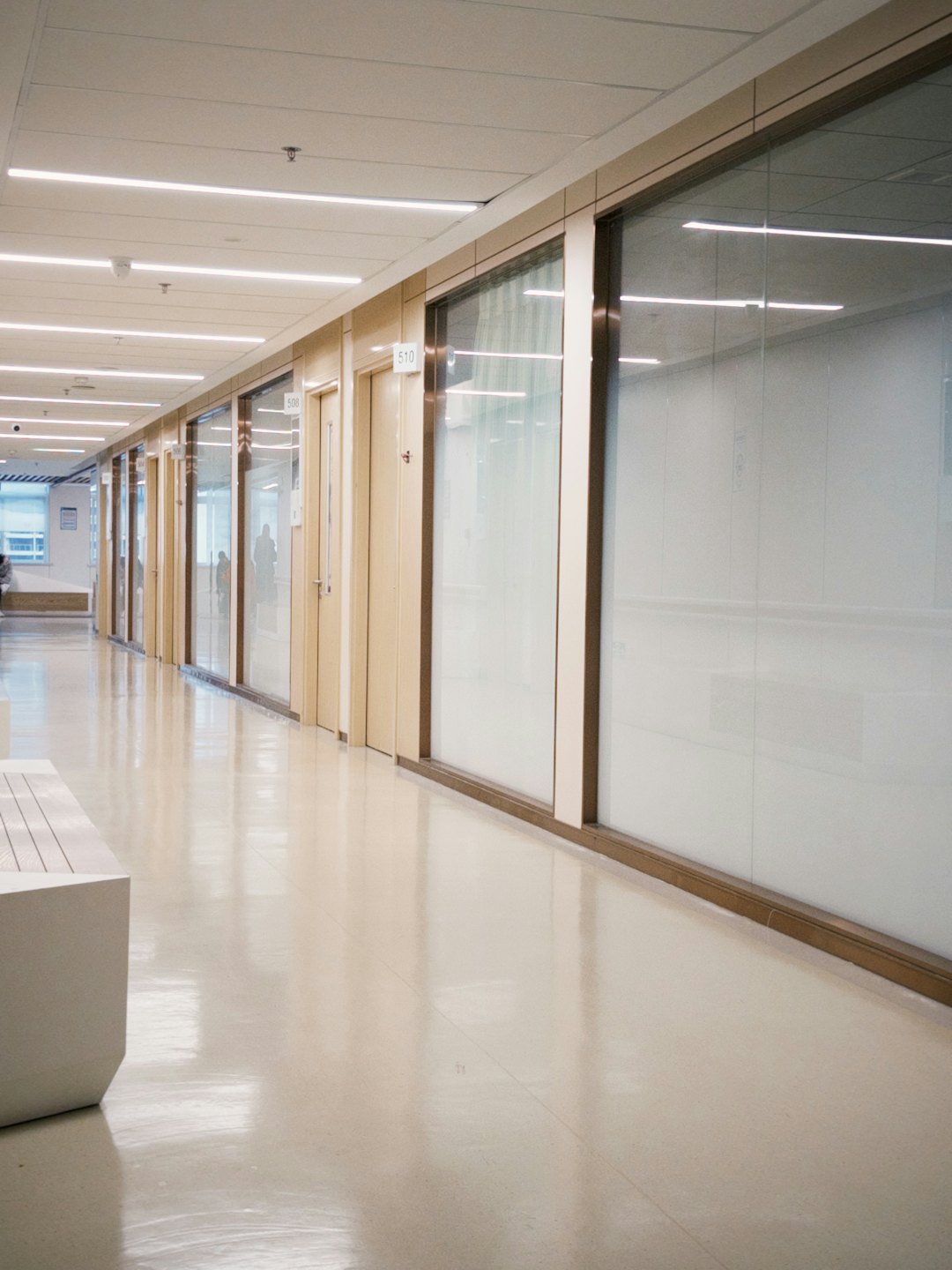 Šiuolaikiniame koridoriuje – medinės durys ir stikliniai kambariai.